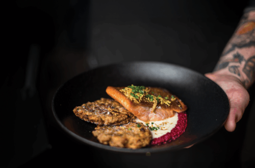 The trout is served with bacon-infused beet purée and squash galette.